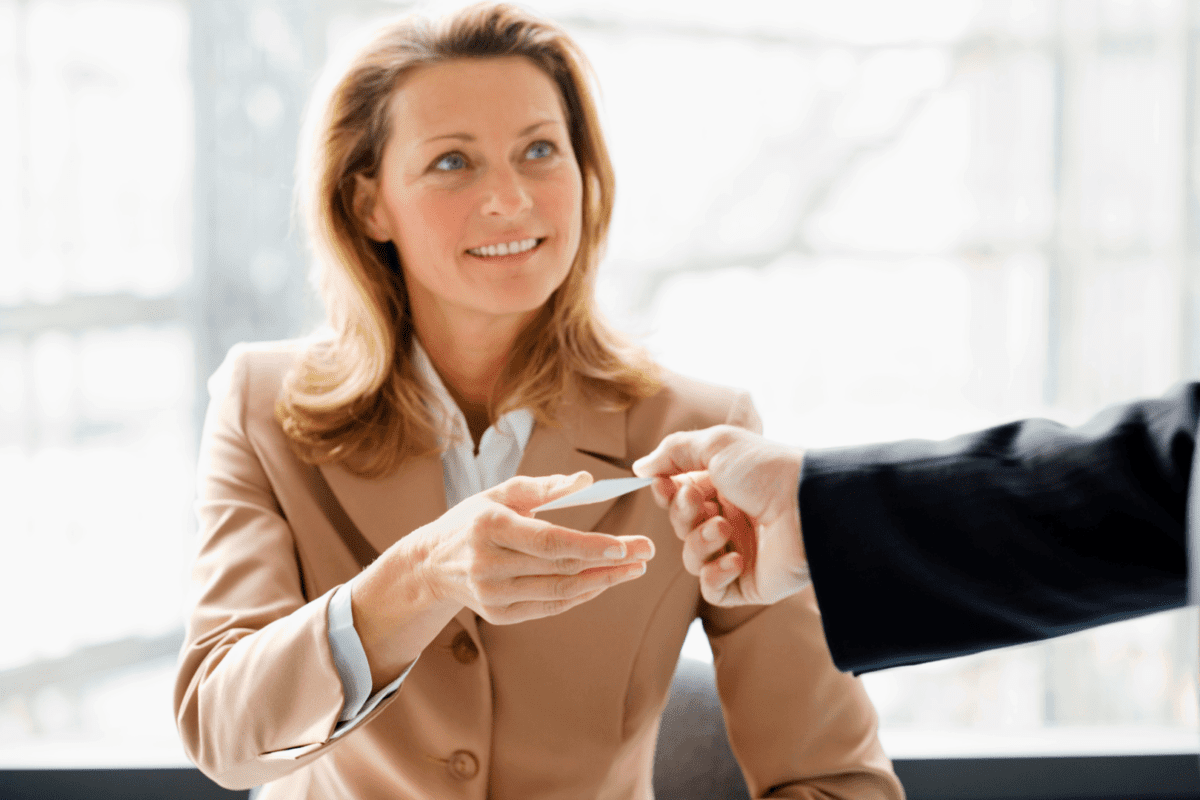 Businesswoman handing a business card to a client, illustrating professional networking and marketing interactions.